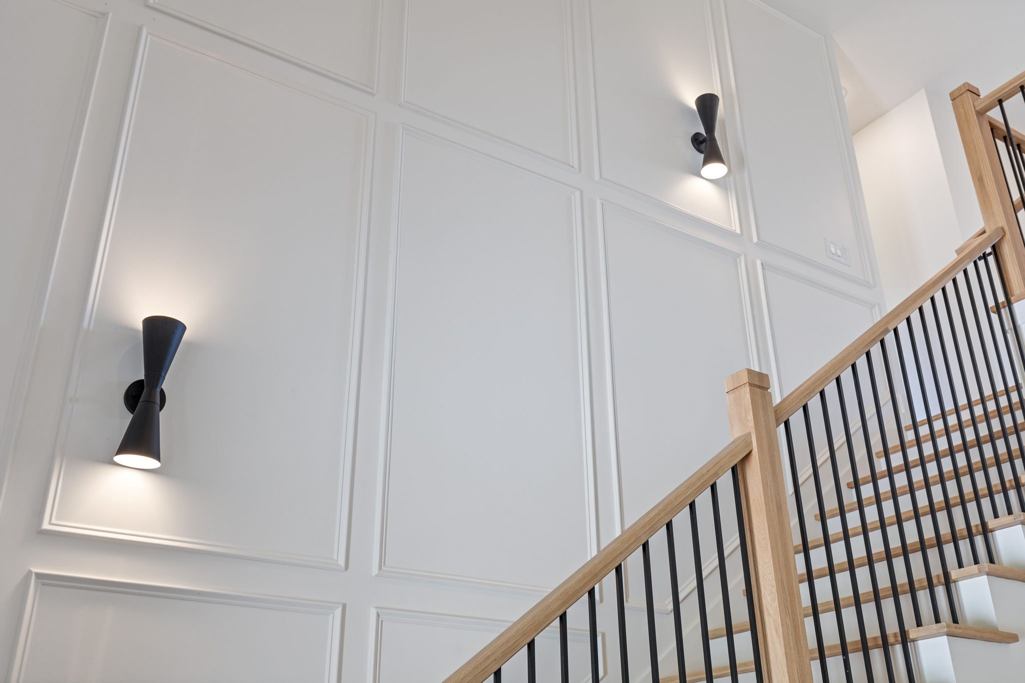 Staircase wainscoting with architectural sconces